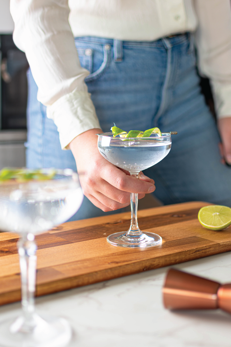 A lifestyle shot of someone picking up a cocktail at the bar